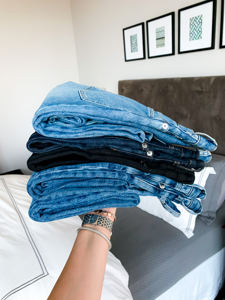 woman holding a stack of jeans 