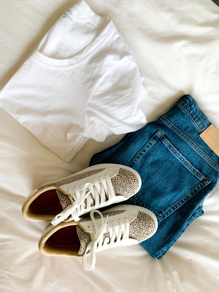 a flat lay of shirt, jeans, and sneakers