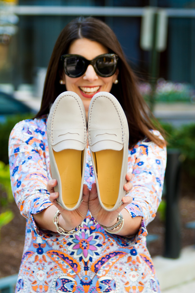 woman holding a pair of grey shoes and smiling 