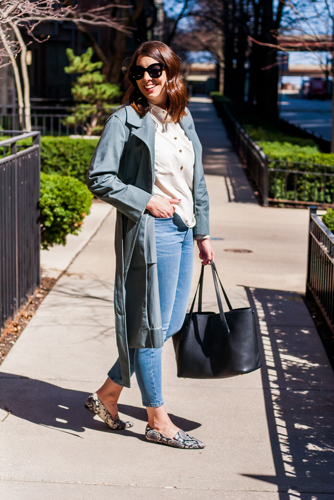 woman wearing a green unique trench coat, jeans, and black bag