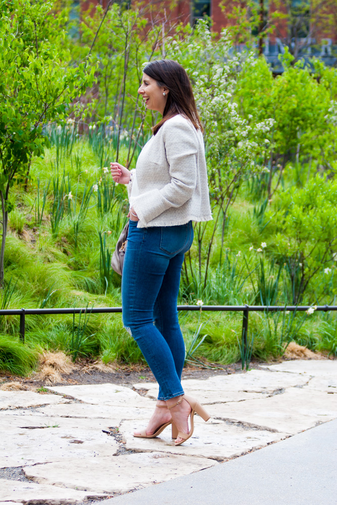 woman standing outdoors wearing white twee jacket, jeans, and white top