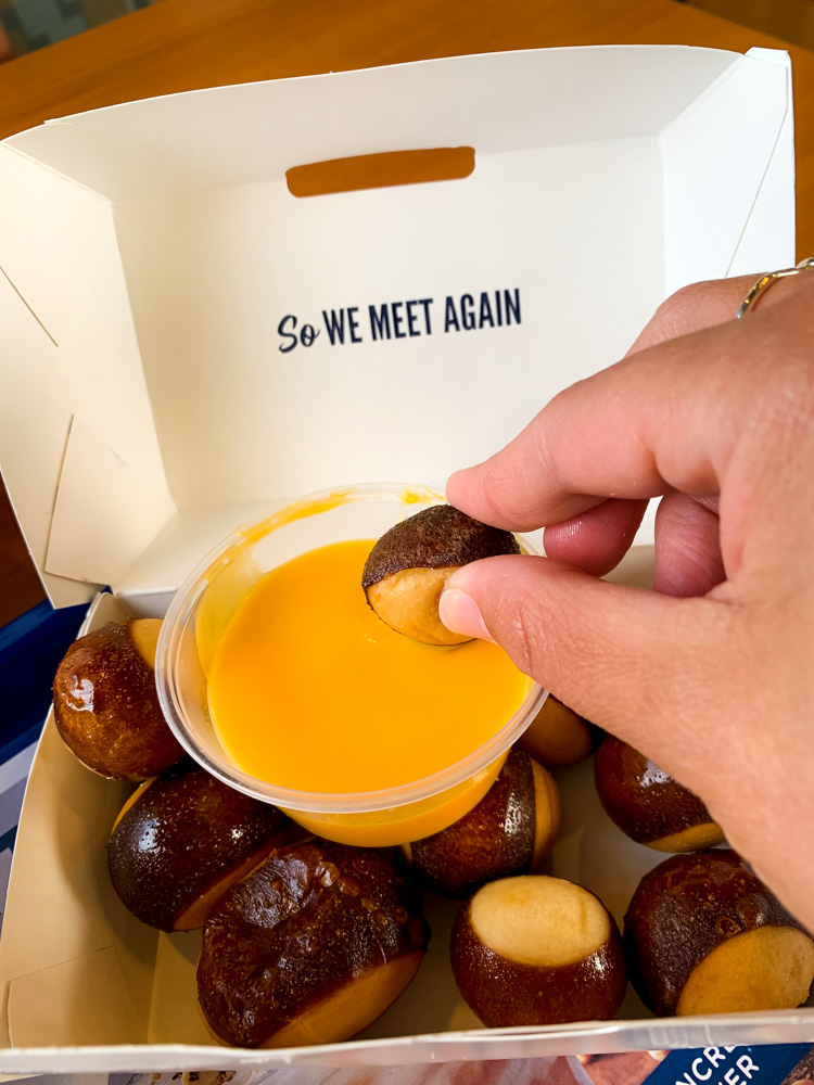 person dipping Pretzel Bites with Wisconsin Cheddar Cheese Sauce