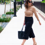 woman wearing turtle neck top and black pants and walking in the streets