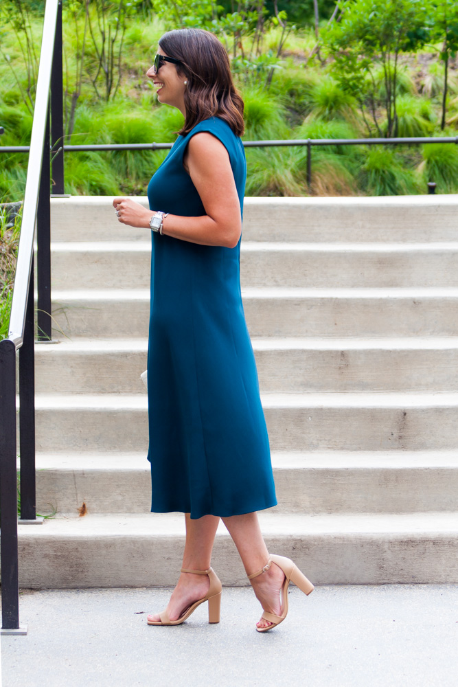 side view of a woman wearing an asymmetric dress  and explaining wedding guest dress codes 