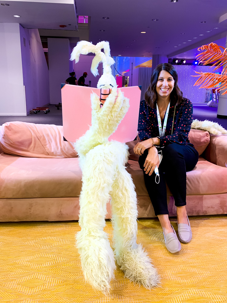 woman with a mascot sitting on a couch at the dr. seuss experience