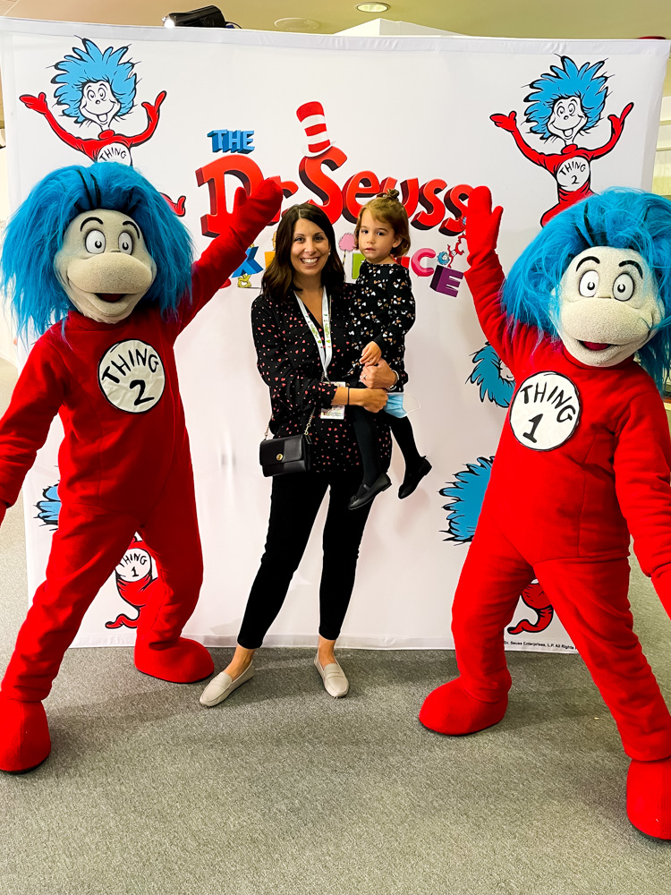 woman carrying her child with a mascots at the dr. seuss experience