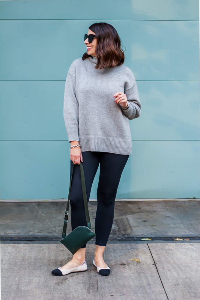 woman wearing plush cashmere sweater and holdign a green bag
