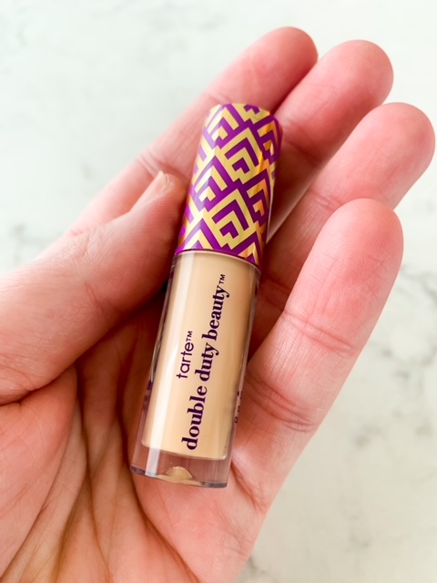 woman holding Tarte Cosmetics Shape Tape Concealer