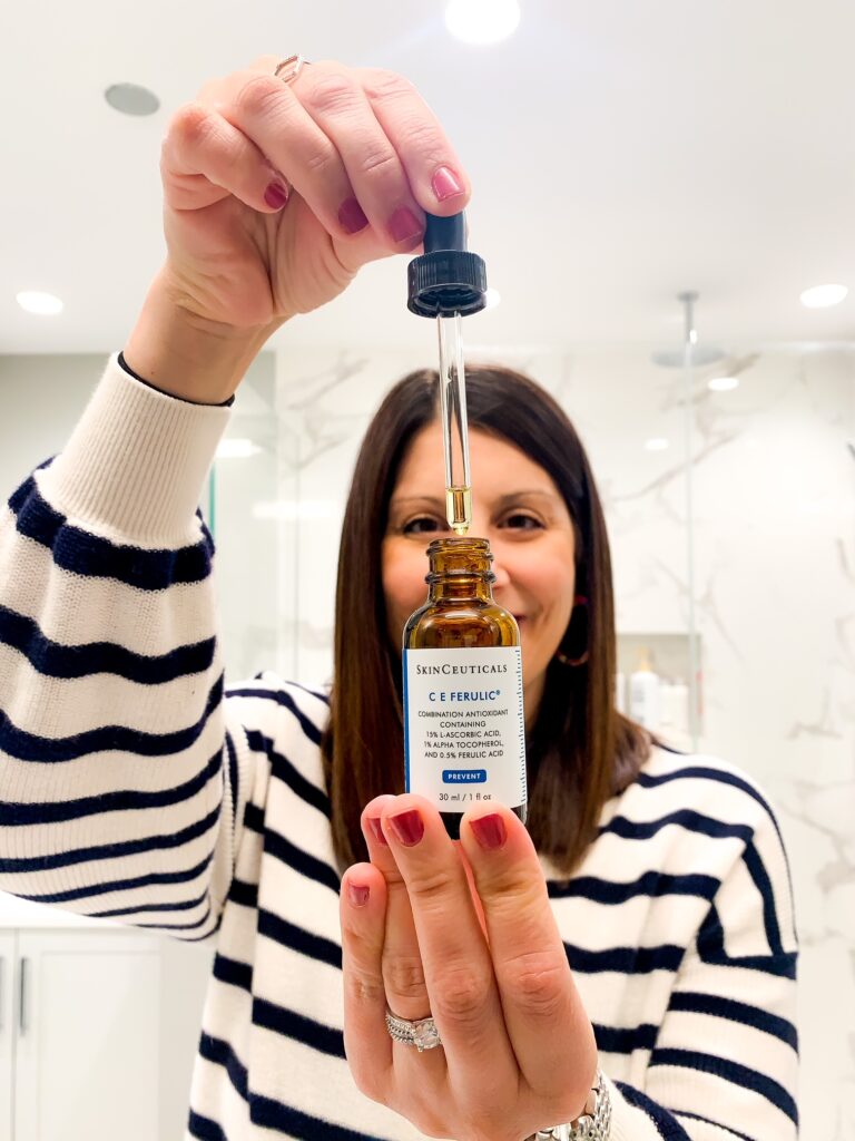 woman getting some drops of skinceuticals C E Ferulic out of bottle