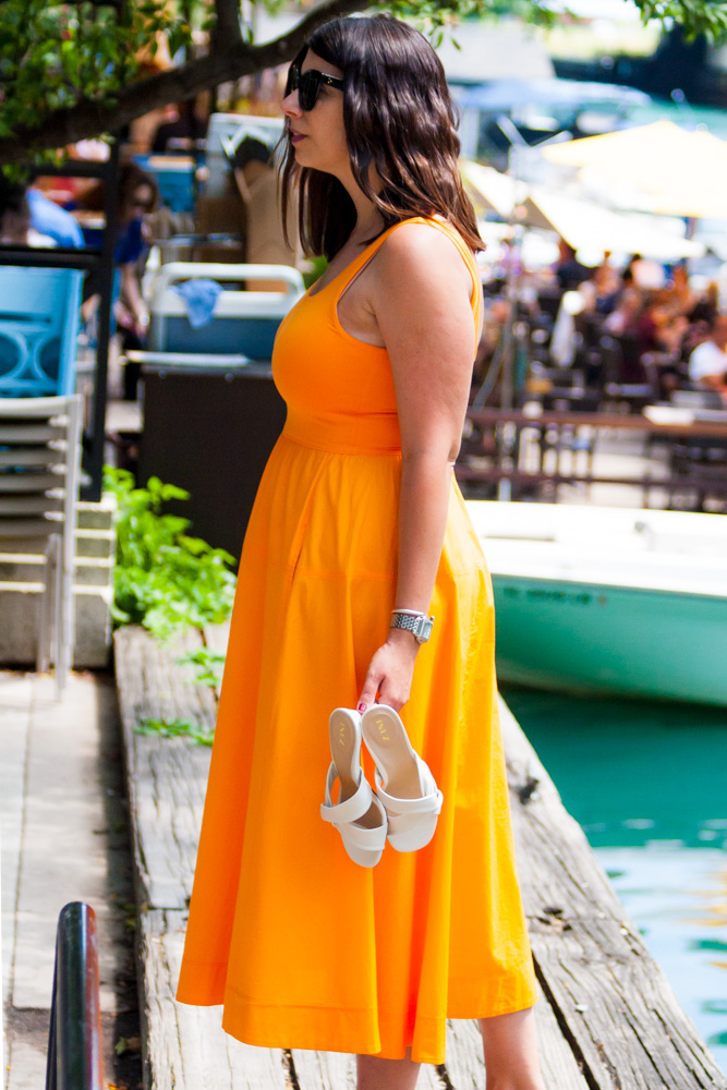 woman in orange dress and holding a pair of INEZ Shoes 