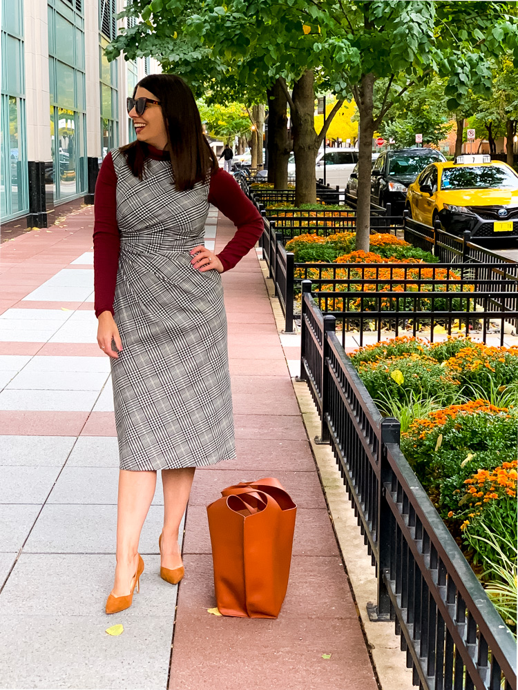 Woman standing on sidewalk showing how to wear plaid this fall