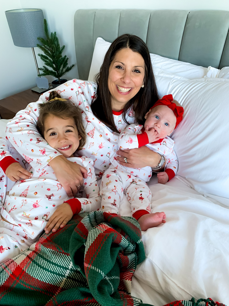 a mom with two daughters in matching christmas pj's laying on a bed